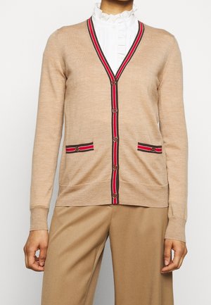 Beige stickad cardigan med V-hals, röda och marinblå randiga detaljer, två framfickor och dekorativa knappar. Slät textur och figurnära stil.