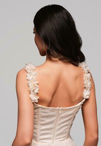 Trägerloses cremfarbenes Kleid aus strukturiertem Stoff mit floralen Akzenten an den Schulterträgern. Verfügt über einen versteckten Reißverschluss hinten.