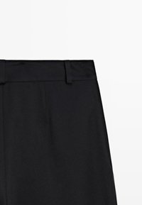 Pantalons noirs avec une texture lisse, présentant un devant plat, deux passants de ceinture et une coupe cintrée à la taille.