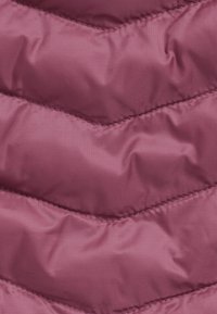 Primo piano di un tessuto trapuntato viola con cuciture diagonali che creano sezioni imbottite.