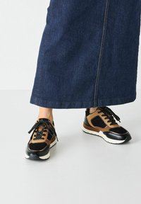 Baskets noires et marron en matières suédées et synthétiques, avec un bout rond, un design à lacets et une épaisse semelle blanche.