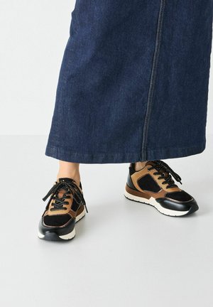 Black and brown sneakers with suede and synthetic materials, featuring round toe, lace-up design, and a thick white sole.
