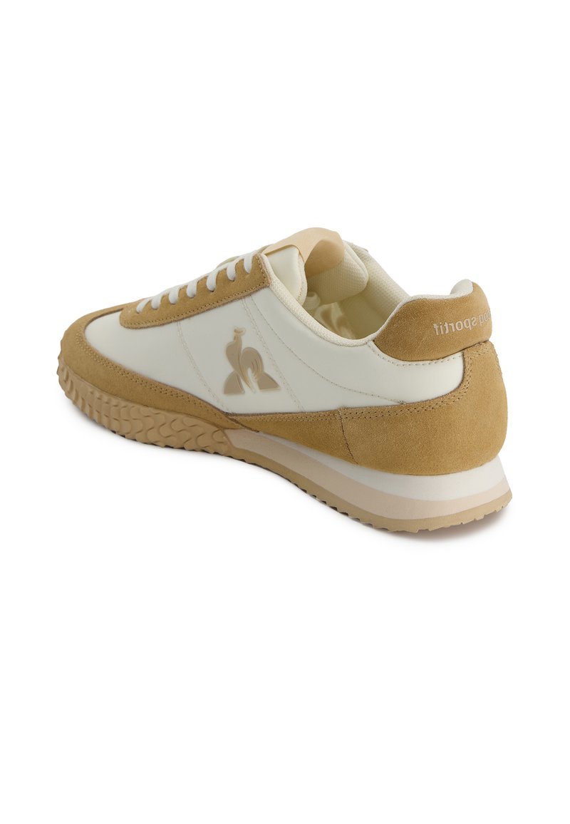 Baskets en cuir et suède crème et beige, présentant un bout rond, des accents texturés, des lacets blancs et une semelle en caoutchouc avec une bonne adhérence.