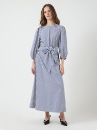 Striped maxi dress in blue and white. Features puffed sleeves, a bateau neckline, and a knotted waist detail. Smooth cotton fabric.