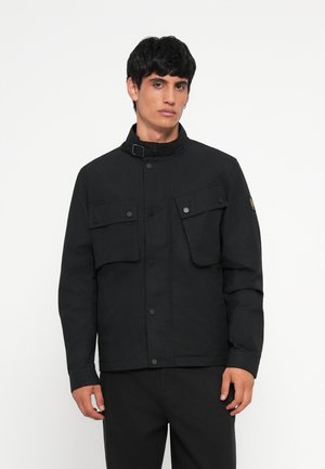 Black jacket with a high collar, two front pockets, snap buttons, and a patch on the sleeve. Made of a smooth, textured fabric.