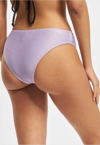 Ibolya színű bordázott bikini alsó, alacsony derékkal, sima textúrával és mérsékelt hátfedéssel, ívelt varratokkal.