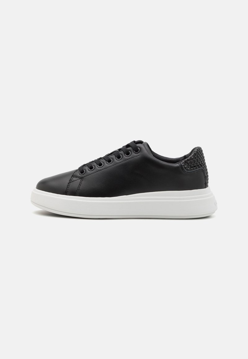 Black leather sneakers with a smooth finish, white rubber sole, and textured back detail. Features lace-up closure and stitched accents.