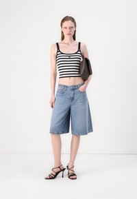 Pruhované černobílé crop top s širokými modrými denimovými šortkami, černými sandály na vysokém podpatku a tmavě hnědou kabelkou. Hladký materiál a ležérní design.