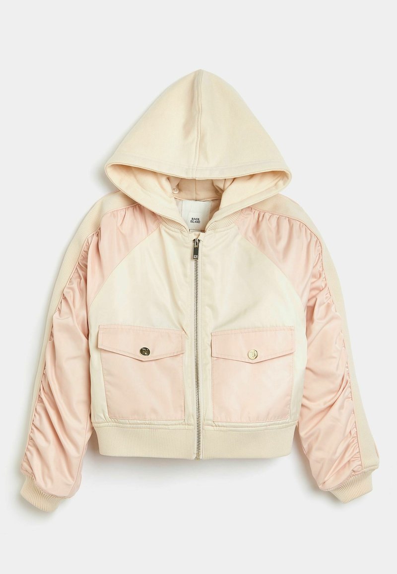 Veste à capuche raccourcie avec des blocs de couleur crème et rose clair, fermeture éclair, deux poches avant, et poignets et ourlet côtelés. Finition en tissu doux.