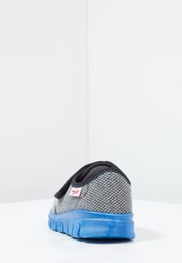 Szare siatkowe sneakersy z wyściełanym czarnym kołnierzem, niebieską podeszwą i czerwoną metką. Posiadają rzep do bezpiecznego zapięcia.