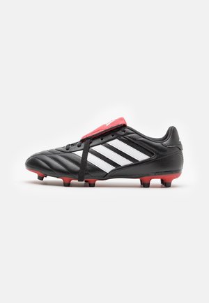 Chaussure de football Adidas noir et blanc avec des crampons rouges et une couverture de lacet rouge, vue de profil sur un fond blanc.