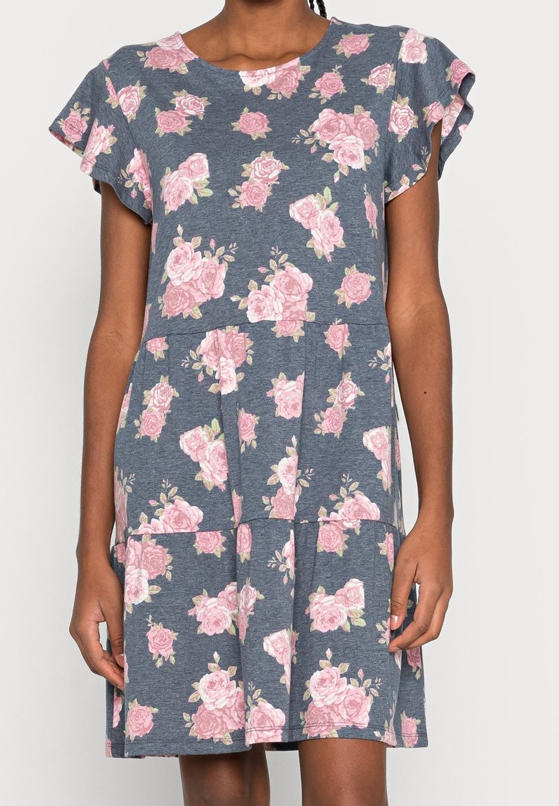 Blommig klänning i mjukt tyg, med en blå botten och rosa rosor, volangärmar, rund halsringning och en flerlagerskjol.