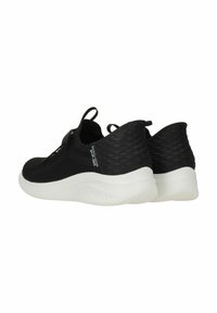 Zapatillas deportivas negras hechas de tela de malla con una parte trasera texturizada, que cuentan con una suela de goma blanca, cordones elásticos y lengüetas para facilitar su uso.
