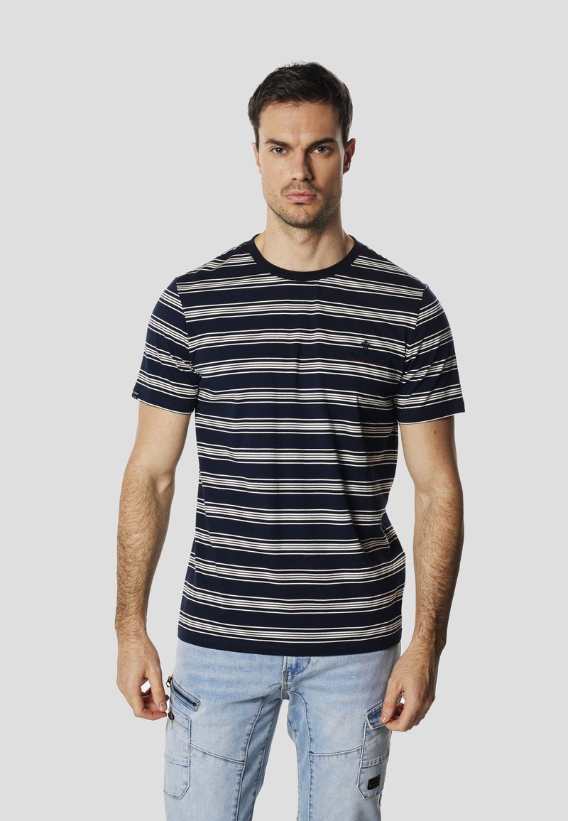 T-shirt à rayures marines avec des lignes horizontales blanches, col rond, manches courtes et détail logo sur la poitrine. Associé à un pantalon cargo bleu clair.