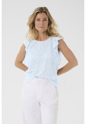 Ljusblå broderad topp med volangärmar, laserskurna blommönster och scallopad nederkant; matchad med ljusa byxor.