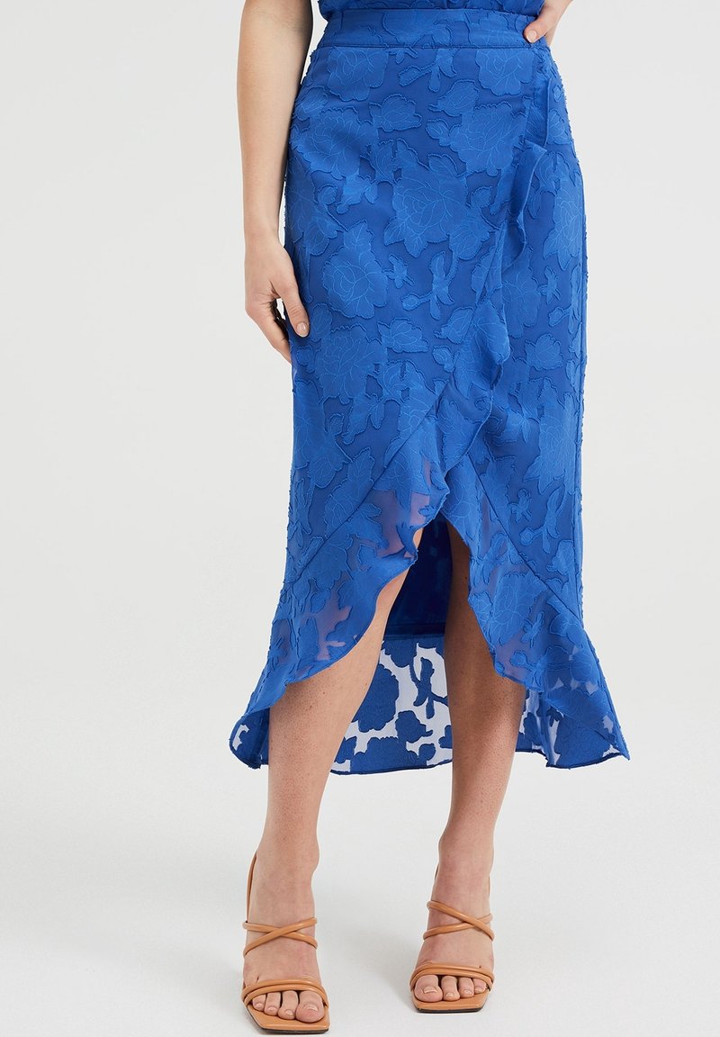 Modrá květinová krajková sukně obal s vysokým rozparkem, má průhledný překryv a vlnitý lem. Spárované se světle hnědými sandály na pásky.