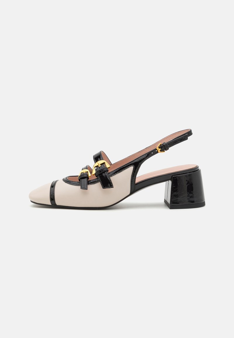 Salto alto em slingback bege e preto com bico fino, acabamentos brilhantes, duas fivelas decorativas e um design de salto bloco.