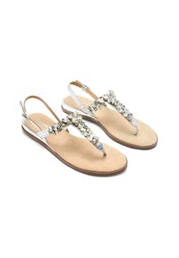 Sandali d'argento con design a fascetta, caratterizzati da un'ornamentazione decorativa di gioiello e una soletta in beige con texture, cinturino alla caviglia regolabile.