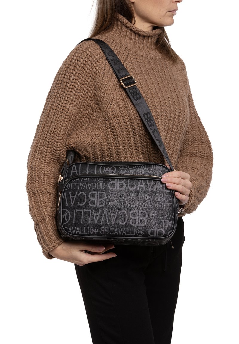 Borsa a spalla nera con design del logo testurizzato, chiusura con zip e tracolla regolabile. Presenta dettagli in hardware dorato e una forma rettangolare.