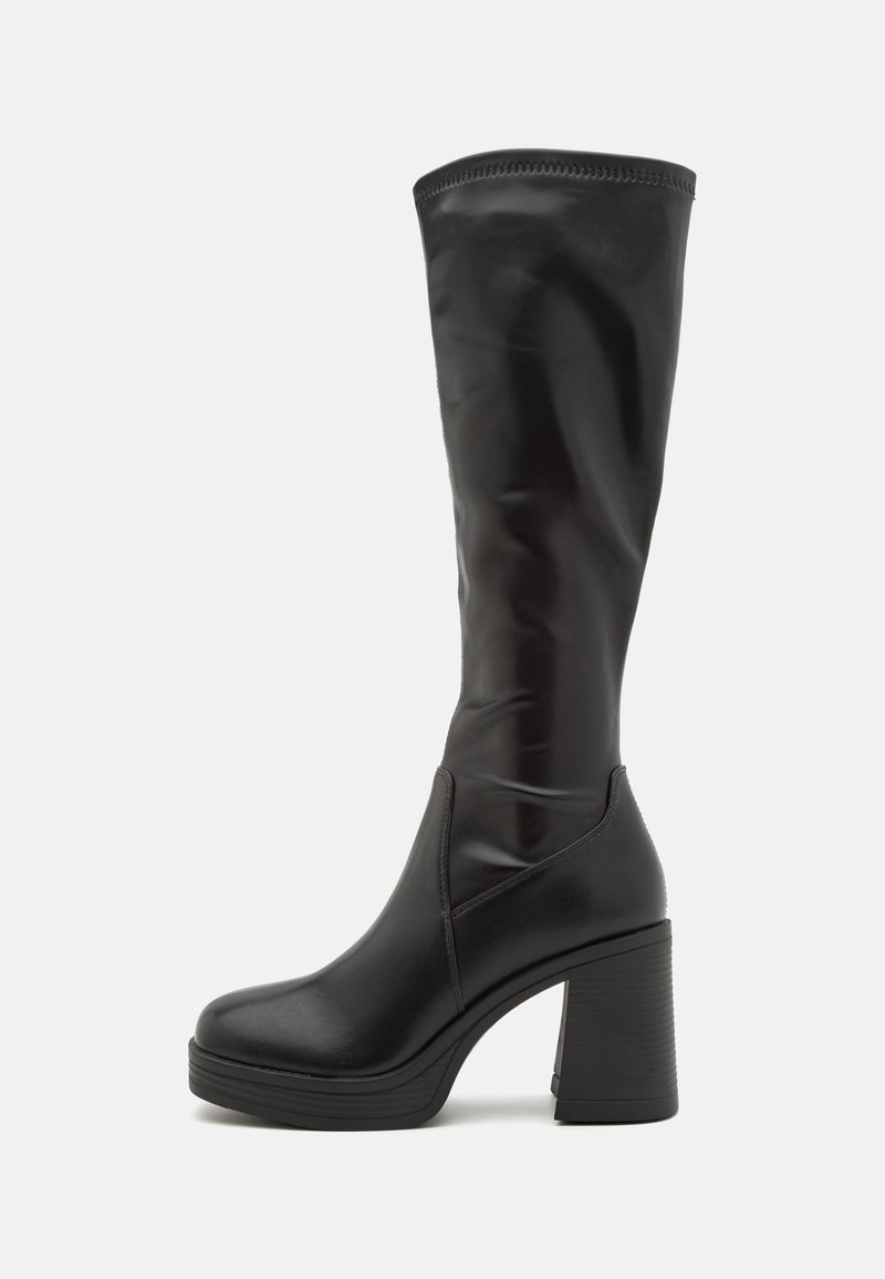 Des bottes noires montantes en cuir lisse, dotées d'un talon épais et d'un design épuré sans embellissements ni motifs visibles.