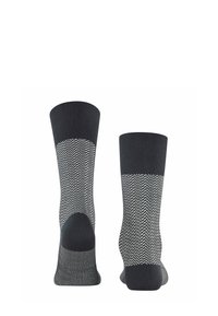 Calze nere con un motivo a spina di pesce in bianco, realizzate in un tessuto morbido. Il design include un bordo a coste e un tallone rinforzato.