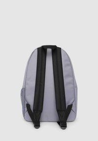 Zaino in tessuto grigio con spallacci neri imbottiti. Presenta una tasca laterale in rete. Parte superiore arrotondata e design slanciato.