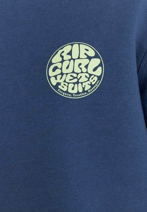 Blauwe sweatshirt met een groot, cirkelvormig geel-groen logo "RIP CURL WETSUITS" met golvende, speelse lettertypes.