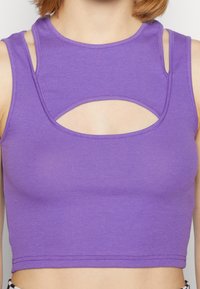 Lila kortärmad tanktopp med ribbad textur, med hög halsringning och utskärning fram och på axlarna.