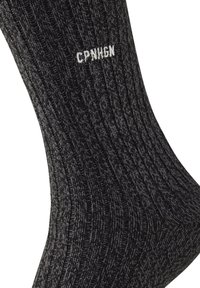 Graue gerippte Socken aus strukturiertem Strickmaterial mit weißem "CPNHGN"-Text in der Nähe des oberen Randes. Das Design zeigt subtile Farbvariationen.
