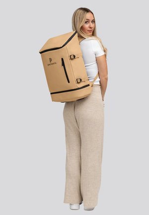 Zaino impermeabile beige con design rettangolare, pattina superiore, dettagli neri e zip laterale. Spallacci regolabili per il trasporto. Logo visibile.