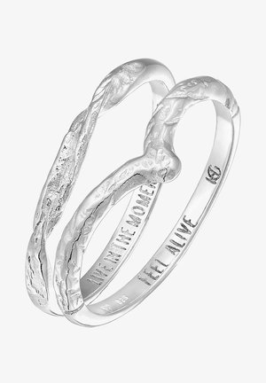 Anillo de plata con un diseño torcido que presenta dos bucles entrelazados, uno texturizado y el otro liso, grabados con "VIVE EN EL MOMENTO" y "SIENTE VIVO".