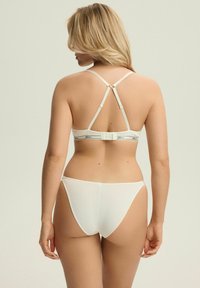 Biały zestaw bielizny z usztywnianym stanikiem na regulowanych ramiączkach i zapięciem na haftek, w komplecie z dopasowanym dołem o ryflowanej fakturze.