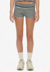 Gestreepte zwart-witte shorts met een brede tailleband, van zachte stof, gecombineerd met crèmekleurige sokken en lichtgekleurde sneakers.