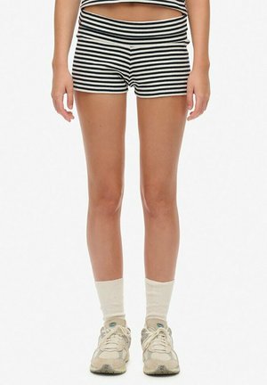 Shorts a righe bianchi e neri con un ampio elastico in vita, tessuto morbido, abbinati a calze color crema e sneakers di colore chiaro.