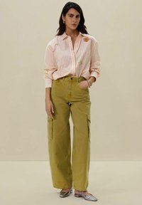 Chemise rayée couleur pêche clair avec broderies florales ; pantalon cargo taille haute vert olive ; ballerines en métal argenté brillantes ; coupe décontractée ; pas de motifs visibles.