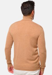 Hellbrauner Rollkragenpullover aus weichem, strukturiertem Strickstoff. Eng anliegendes Design mit gerippten Bündchen und Saum, von hinten zu sehen.