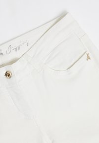 Vita bomull jeans med en stilren design, guldtonad knappstängning och en liten dekorativ bi-accent på framlommen.