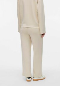 Beige sweatset met een lange mouwen top en bijpassende broek. Zachte stof met een comfortabele pasvorm, wijde pijpen en ribgebreide manchetten.