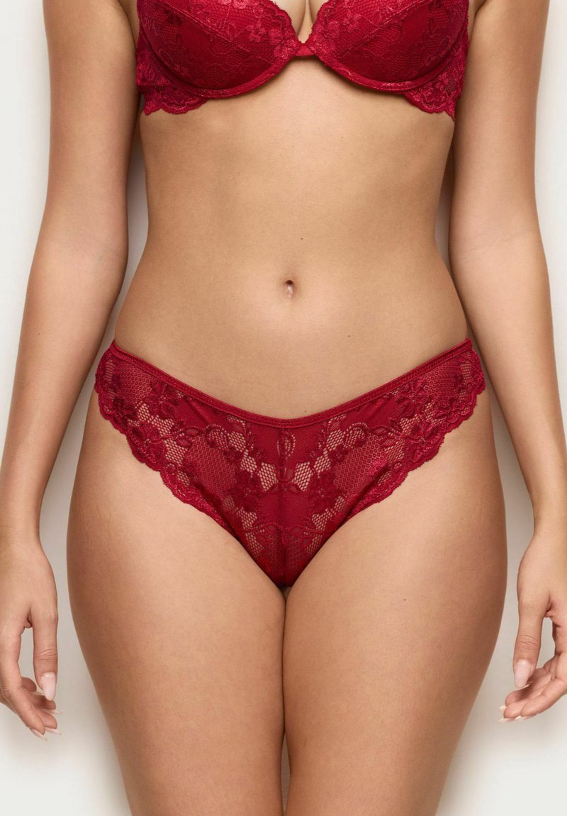 Röd spetsunderkläder med blommönster, en genomskinlig textur och vågiga kanter, med låg midja och intrikata detaljer.