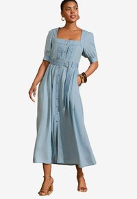 Light blue denim maxi dress with short puff sleeves, square neckline, front buttons, pleats, and a belted waist. Features a relaxed fit.