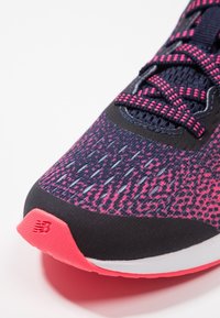 Lehké běžecké boty s vrškem z námořnického a růžového síťového materiálu, texturovaným designem a růžovou podešví s výrazným logem.