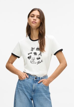 T-shirt de algodão branca com borda preta, apresentando uma variedade de ilustrações gráficas, incluindo um gato e símbolos icónicos, em tinta preta.