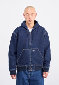 Mørkeblå denim hoodie med frontlynlås, to store lommer, ribbede manchetter og hætte med snoretræk. Har synlige stikninger som accent.