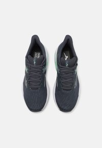 Donkerblauwe sport schoenen met een gestructureerde bovenkant, groene accenten en witte zolen. Heeft een vetersluiting en een gevoerde kraag voor comfort.