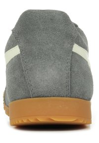 Scarpa in suede grigio vista da dietro, con una finitura testurizzata, strisce bianche a contrasto e una suola in gomma con un motivo a tassello triangolare.