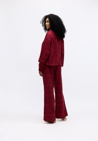 Rød rutete loungewear-sett med en løs knappedrakt og brede bukser. Mykt stoff med avslappet passform og uformelt design.