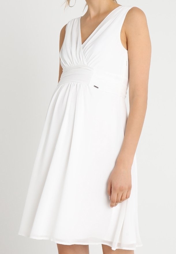Vit ärmlös klänning med V-ringning, samlad midja och flödande kjol. Tillverkad av lätt tyg med en slät textur.