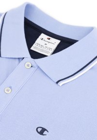 Jasnoniebieska koszulka polo z teksturowanej tkaniny, z granatowym kołnierzykiem w białe paski, trzema guzikami i małym czarnym logo na piersi.