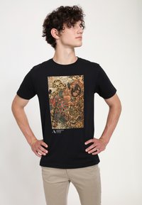 Camiseta negra con un estampado gráfico colorido de una obra de arte con tigres y figuras, hecha de suave tela de algodón, en un corte clásico.