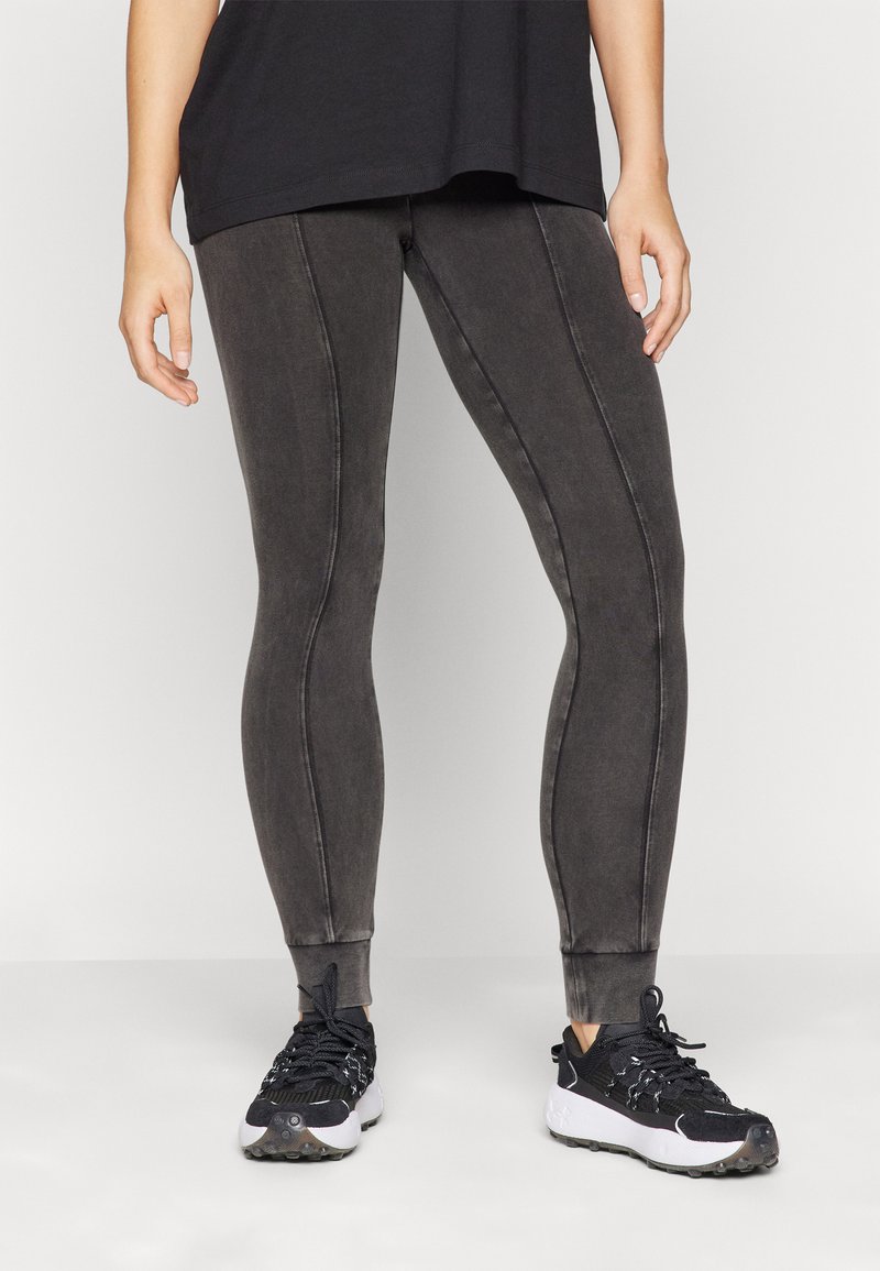Leggings skinny neri con cuciture tono su tono, vestibilità affusolata e polsini alle caviglie. Abbinati a scarpe da ginnastica nere con suole bianche.